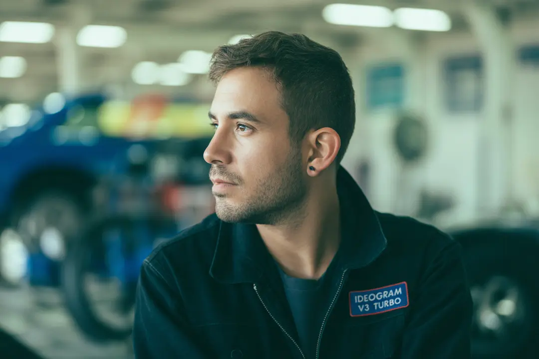 color film portrait of a man looking to the side with a shallow depth of field, high ISO film grain, wide aperture motion blur effect, "Ideogram V3 Turbo" mechanic garage style badge on the shoulder