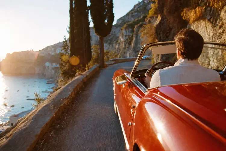 Vintage convertible on an Amalfi cliff road at golden hour