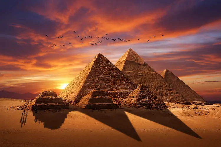 Add a dramatic golden hour sunset sky with deep orange and magenta clouds, and a flock of birds flying in the distance