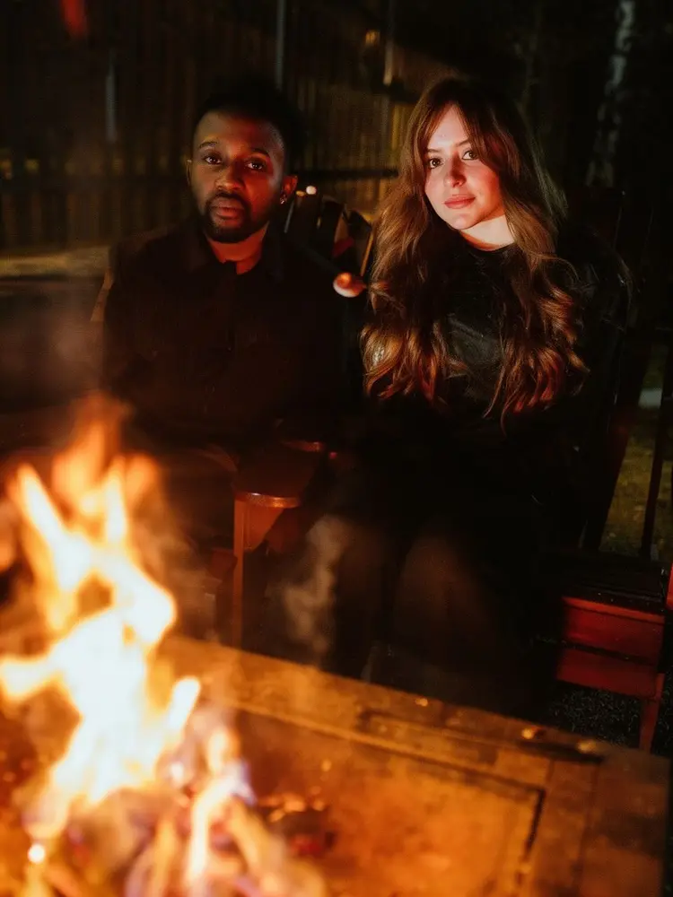 replace the couple next to the fire in image 1 by the man in image 2 and the woman in image 3